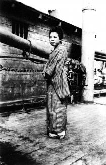 Black & white photo of a Japanese woman wearing a kimono on the deck of a ship.