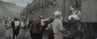 Black & white photo of Japanese Canadian families saying goodbye through windows of train passenger car.