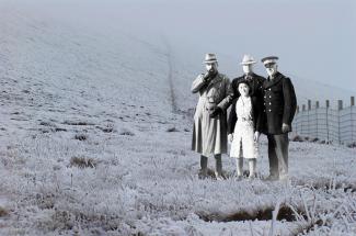 Black & white photo of three caucasian male officers standing behind Japanese Canadian woman.