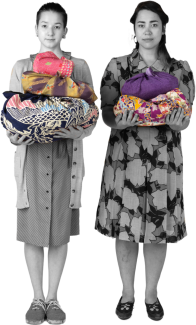 Two young persons of Japanese descent stand holding colourful bundles of fabric.